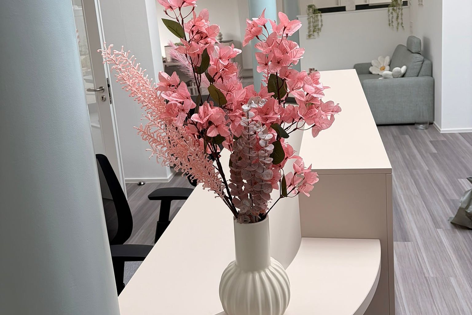Vase mit pinken Kunstblumen auf einem modernen Tisch in einer hellen Einrichtung.