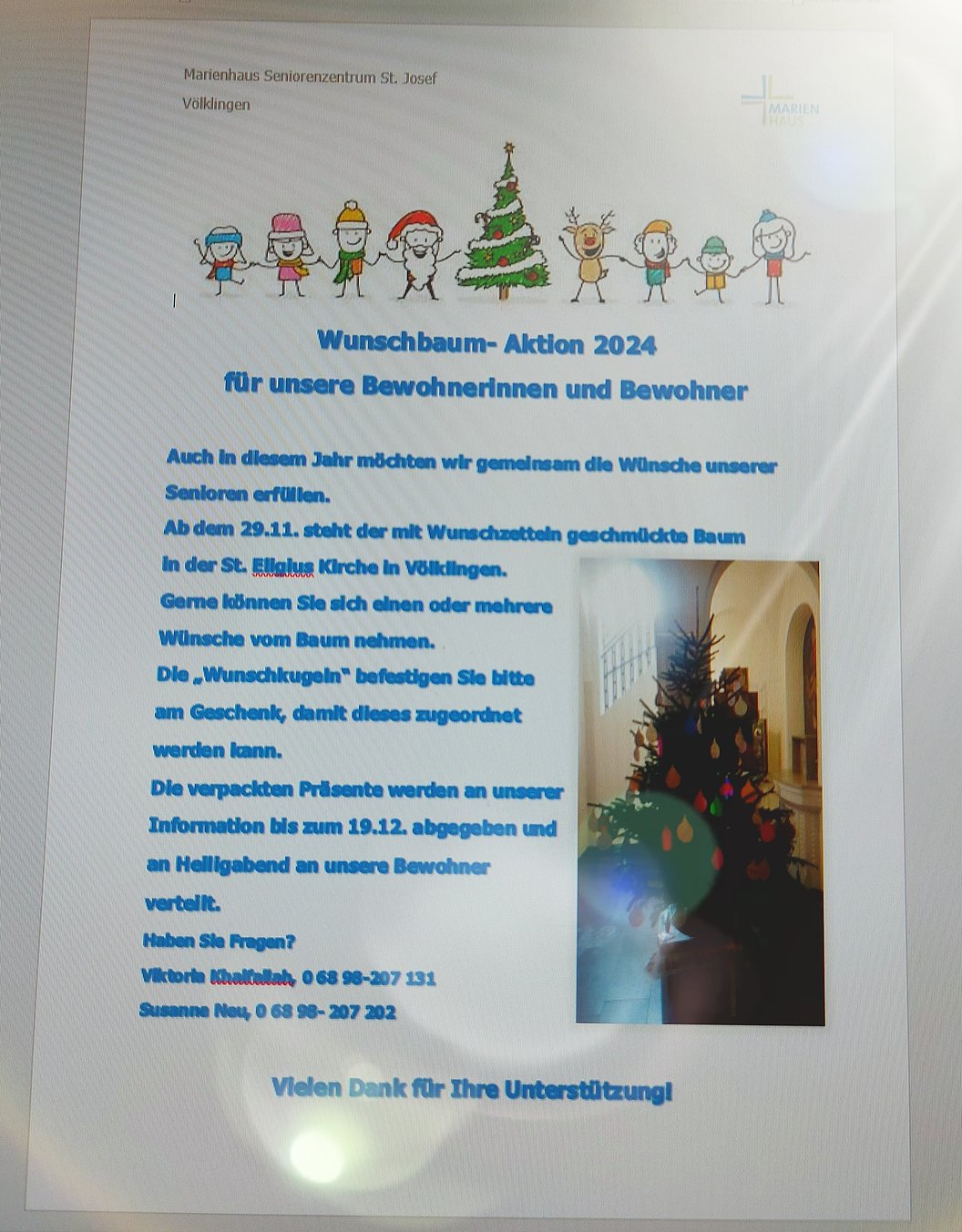 Aushang mit Weihnachtsmotiv und Text zur Wunschbaum-Aktion 2024 für Bewohnerinnen und Bewohner, daneben ein Foto eines geschmückten Weihnachtsbaums in einem Innenraum.